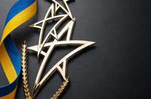 Two gold metal stars next to a yellow and blue ribbon on a black background.