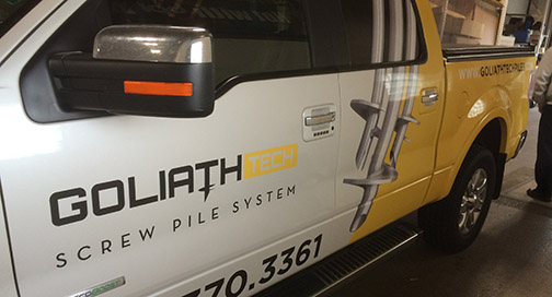 A white truck in a garage showing a decal on the driver's door.