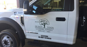 A white truck in a garage showing a decal on the driver's door.