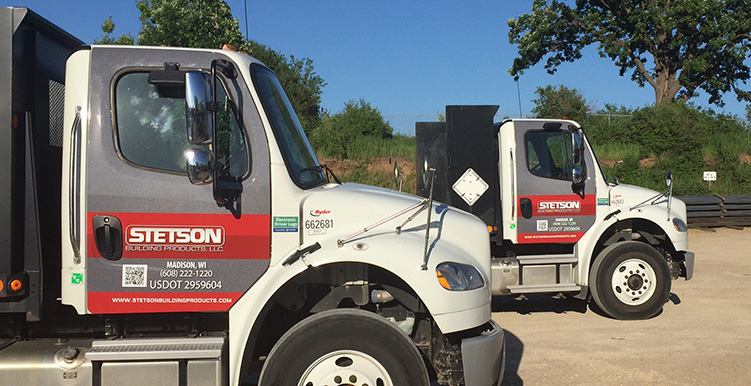 Two large white trucks with custom door graphics.