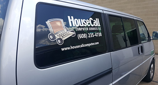 A silver van showing a decal on the passenger's back window.