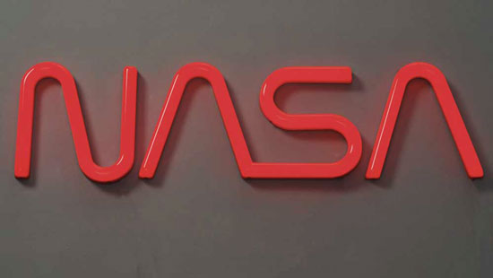 Bright red letters "NASA" on a dark gray wall.