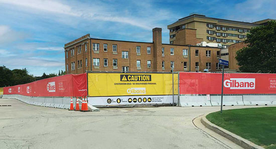 Yellow and red semi-transparent construction banners hanging on a chain-link fence.